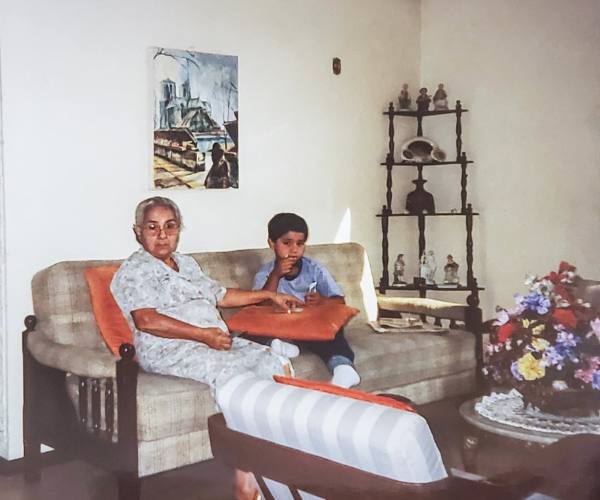 Daniel Patiño sits with his grandmother on a sofa in Colombia
